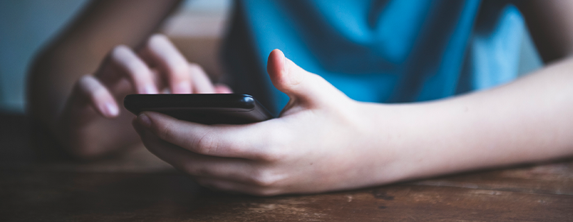 Billede af ung person med mobiltelefon i hånden.