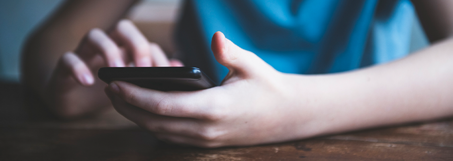 Billede af ung person med mobiltelefon i hånden.